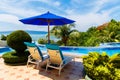 View from a hotel with sun loungers and a parasol in front of the infinity pool on the tropical beach and beautiful sea with boats Royalty Free Stock Photo