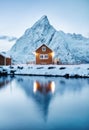 View on the house in the Sarkisoy village, Lofoten Islands, Norway. Landscape in winter time during blue hour. Mountains and water