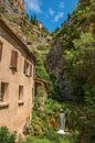 View of houses near creek and bluff with church on top of cliff in Moustiers-Sainte-Marie. Royalty Free Stock Photo