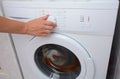 View on how a woman is turning on of the washing machine. A woman is choosing a washing mode on the washing machine