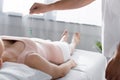 View of hypnotist standing near woman on massage table and holding green stone