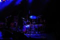 View on illuminated empty live stage with blue illuminated drum percussion kit and microphones focus on cymbal right of center