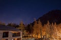 View of illuminated ski resort by pine trees and mountain during starry night
