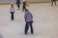 View of indoor ice rink where woman is teaching child to skate.