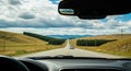 View from Inside a Car Looking Down a Long Open Road Through Rolling Hills and Clouds car interior windshield Royalty Free Stock Photo