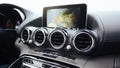View from inside a car on a part of dashboard with a navigation unit and blurred street in front of a car Royalty Free Stock Photo