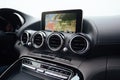 View from inside a car on a part of dashboard with a navigation unit and blurred street in front of a car