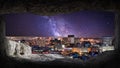 View from the inside of the cave to the night panorama of the city, milky way in the background