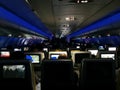 View from inside the plane in mid-flight, low lights, with blue LEDs and emergency light, scenery with rear perspective of the Royalty Free Stock Photo