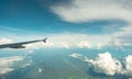 View from inside plane through plane window over blue sky, white clouds and green mountain. Commercial airline flight for summer Royalty Free Stock Photo