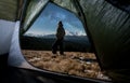 View from inside a tent on the male tourist in his camping in the mountains at night Royalty Free Stock Photo