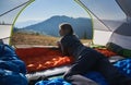 Girl lying in tent and admiring mountain landscape. Royalty Free Stock Photo
