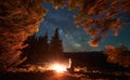 Silhouette of hiker resting by the fire in fresh air under starry sky. Royalty Free Stock Photo