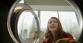 View from inside washing machine on Caucasian beautiful happy woman opening up and taking out clean washed clothes. Royalty Free Stock Photo