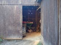 View inside the wooden barn through the open door. Old barn with a tractor inside. Sun rays falling into a country house. Royalty Free Stock Photo