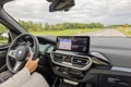 View interior of BMW iX3 M-sport electric car driving along highway with female driver.