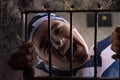 View through iron door with prison bars on male prisoner holding Royalty Free Stock Photo