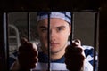 View through iron door with prison bars on young male prisoner h Royalty Free Stock Photo