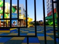 view of the iron figured fence and the playground with multi-colored swings, slides and a rubber coating on the ground
