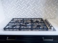 View of an iron stove top with stainless steel knobs inside a kitchen with a nice backsplash Royalty Free Stock Photo