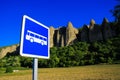 View on isolated bus stop sign against rural field, trees, needle like sharp bizarr rock formations Les PÃÂ©nitents and blue sky Royalty Free Stock Photo