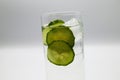 View on isolated glass with sparkling tonic water, cucumber slices, gin and ice cubes