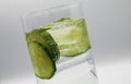 View on isolated glass with sparkling tonic water, cucumber slices, gin and ice cubes