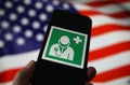 View on isolated mobile phone screen with international health and medical doctor symbol. Blurred waving american flag background.
