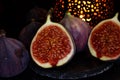 View on isolated raw ripe fig half with group of figs  on black slate stone illuminated by oriental candle lamp Royalty Free Stock Photo