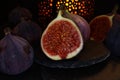 View on isolated raw ripe fig half with group of figs  on black slate stone illuminated by oriental candle lamp Royalty Free Stock Photo