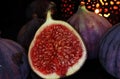 View on isolated raw ripe fig half with group of figs on black slate stone illuminated by oriental candle lamp Royalty Free Stock Photo