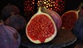 View on isolated raw ripe fig half with group of figs on black slate stone illuminated by oriental candle lamp Royalty Free Stock Photo