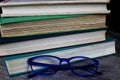 View on isolated stack of old yellowed books on wood table with blue reading glasses Royalty Free Stock Photo