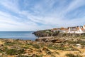 View of the jagged rocky coast and colorful houses in the center of Peniche