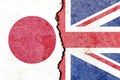 View of Japan and UK national flags on cracked concrete wall background