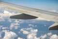 View of jet airplane wing from inside flying over white puffy clouds in blue sky. Travel and air transportation concept Royalty Free Stock Photo