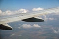 View of jet airplane wing from inside flying over white puffy clouds in blue sky. Travel and air transportation concept Royalty Free Stock Photo