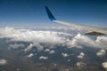 View of jet airplane wing from inside flying over white puffy clouds in blue sky. Travel and air transportation concept Royalty Free Stock Photo