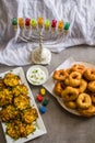 Jewish holiday Hanukkah symbols against white background; traditional spinning top, menorah traditional candelabra, `Sfinj `Donu