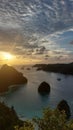 A view of the lagoon with a sunset sky, clear sea, some sailing ships and some small island in wayag, Raja Ampat, West Papua