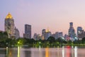 View of lake in Lumpini park with high building of business center district of Bangkok in background at sunset. Travel to Thailand Royalty Free Stock Photo