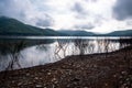 View of the lake and mountains with dead branches of pricky wood weed at the waterside on a cloudy day.