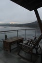 View of lake and mountains at sunrise from terrace with chairs and wooden table Royalty Free Stock Photo