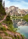 View from lakeside hiking trail to Mount Seekofel mirroring in the clear water of iconic natural mountain lake Pragser Wildsee