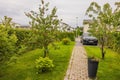 View of landscape design of private house with garden, apple trees and parking for electric car BMW iX3-m sport on autumn day. Royalty Free Stock Photo