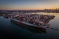 View of a large cargo container ship OOCL docked at a busy harbor with other vessels