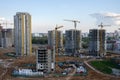 View on the large construction site at urban area. Tower cranes in action with machinery and builders. Multi-storey residential