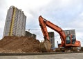 View of a large construction site where earthmoving equipment. Excavator digs the ground to lay pipes and a new road. Tower cranes Royalty Free Stock Photo