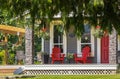 A large front porch with furniture and potted plants. Rustic, country style front porch with red Adirondack chairs Royalty Free Stock Photo