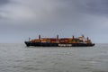 View of a large Hapag-Lloyd container freight ship on the open ocean under an overcast sky